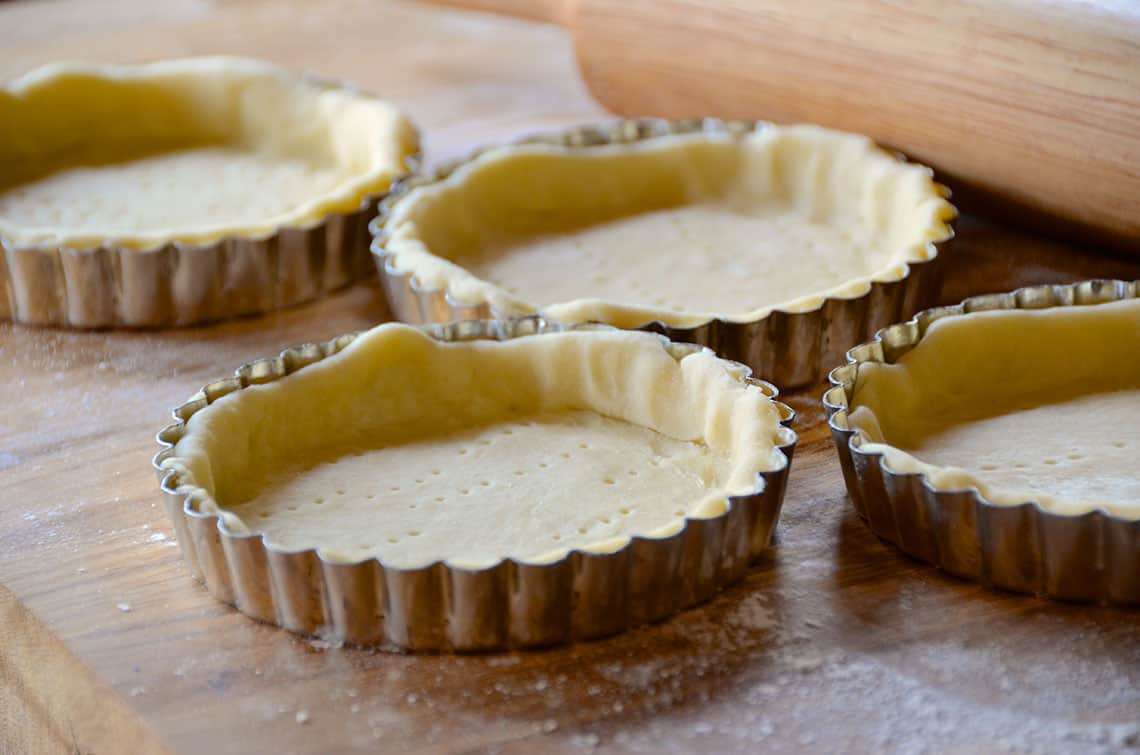 Small tart tins filled with the raw pastry dough