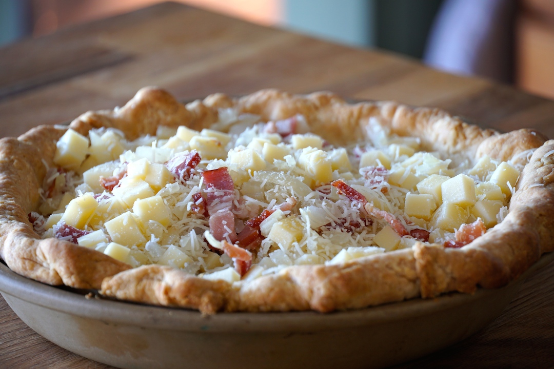 The blind baked pie crust filled with the onions, bacon and cheeses