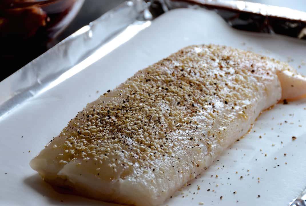 A fillet of cod seasoned and ready to be baked