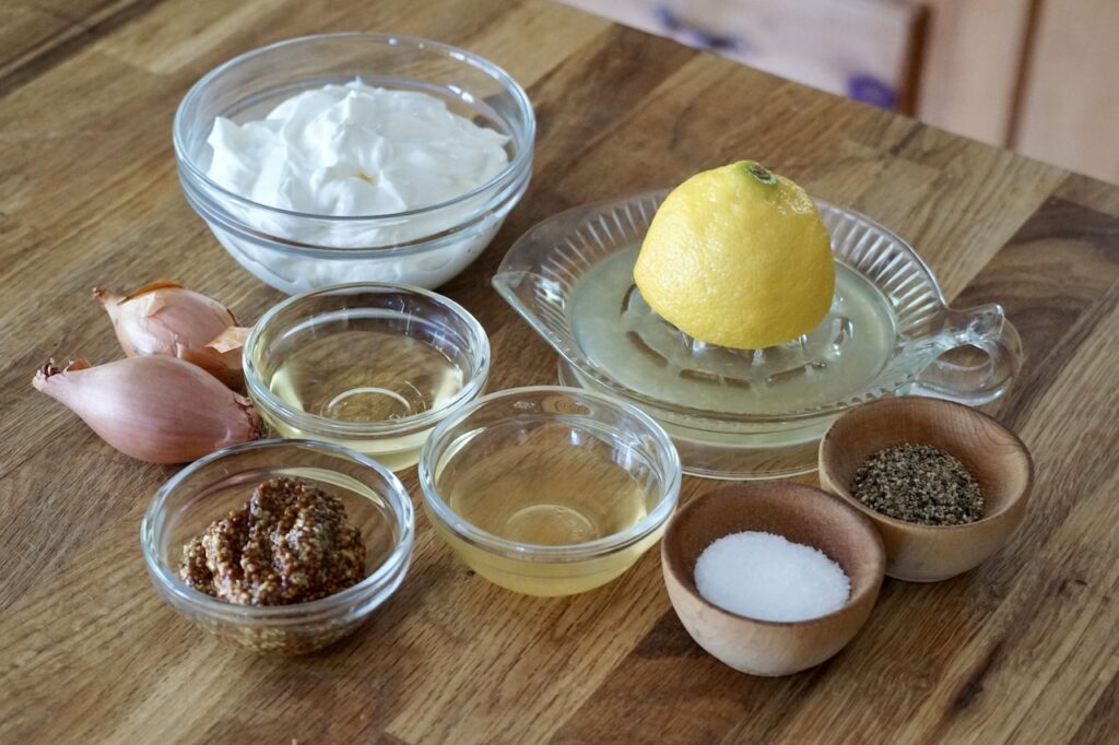 Bowls containing sour cream, apple cider vinegar, grain Dijon mustard, lemon juice and seasoning.