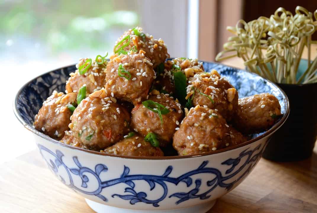 Asian Meatball Recipe served in an attractive bowl garnished with chopped green onions and sesame seeds