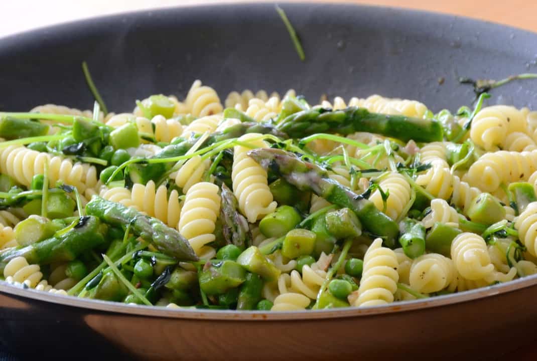 Pea shoots tossed into the skillet