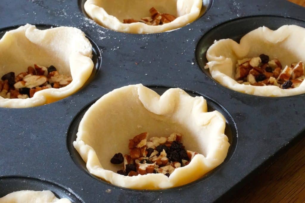 Filling butter tarts with raisins and chopped pecans