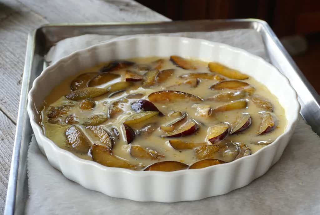Dotting the half-baked custard with the sliced plums