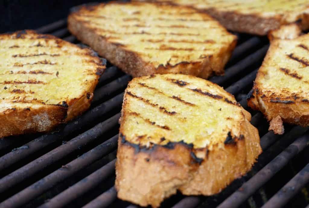 Sliced of garlic-rubbed sourdough being grilled