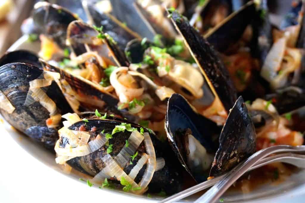 The mussels peaking in a bowl of our Steamed Mussels Recipe