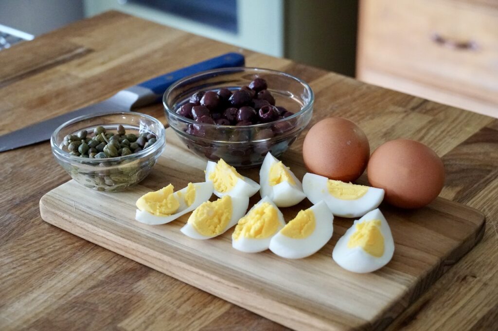 Toppings for the salad include hard boiled eggs, capers and small Niçoise olives.