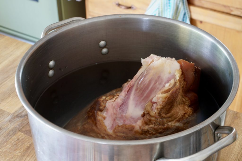 The smoked and cured ham in a large soup pot, ready to be boil