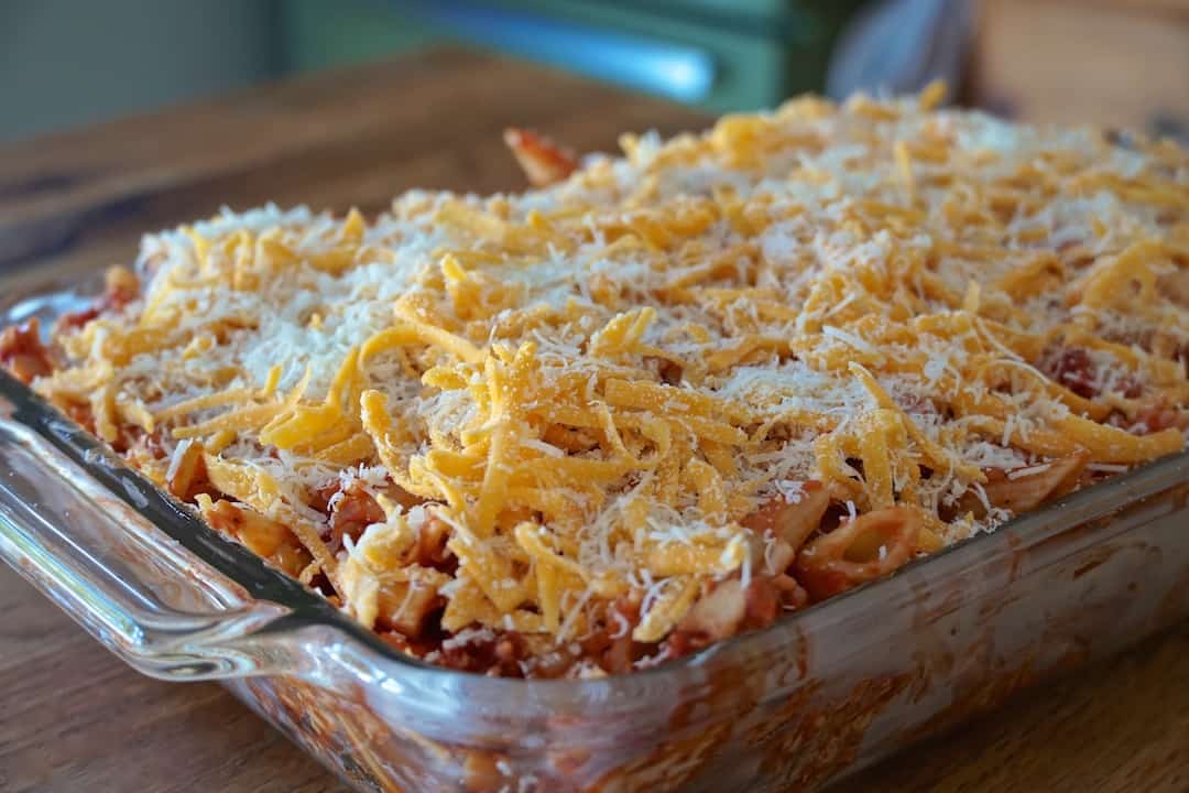 The casserole dish filled and sprinkled with the grated cheeses