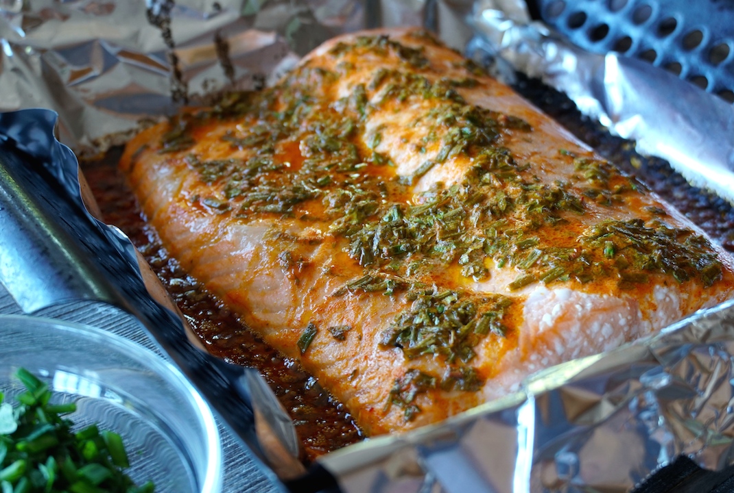 The cooked pieces of salmon topped with the fresh herb sauce