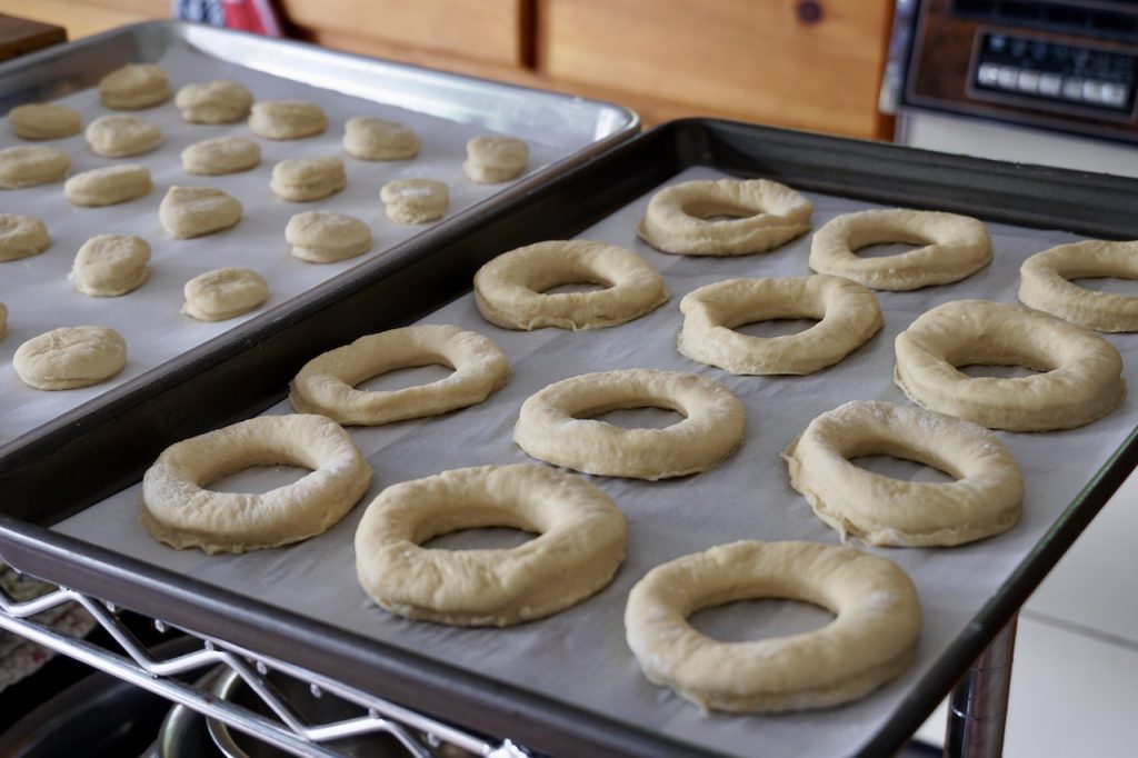 Donuts and holes placed onto baking sheets for a final rise