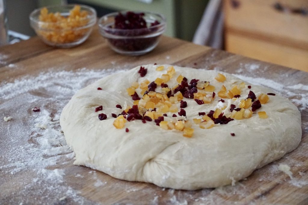 Sprinkling the dough with dried cranberries and orange peel