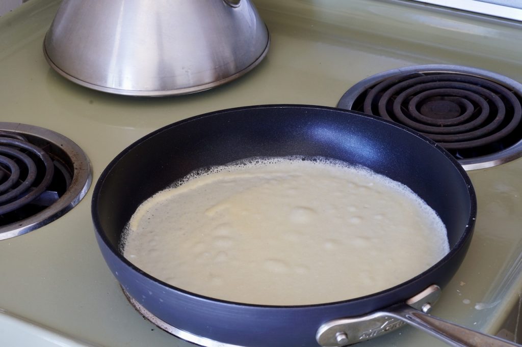 A large skillet coated with the gluten-free pancake batter.