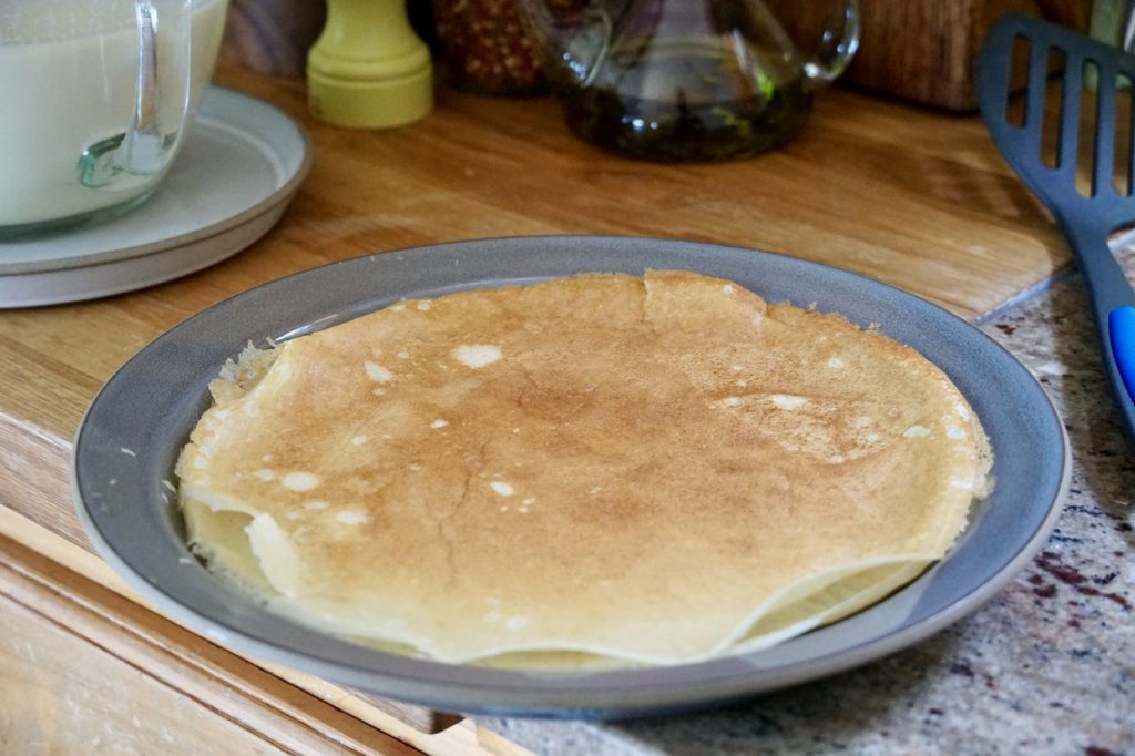 Gluten-free pancakes flipped onto a plate.