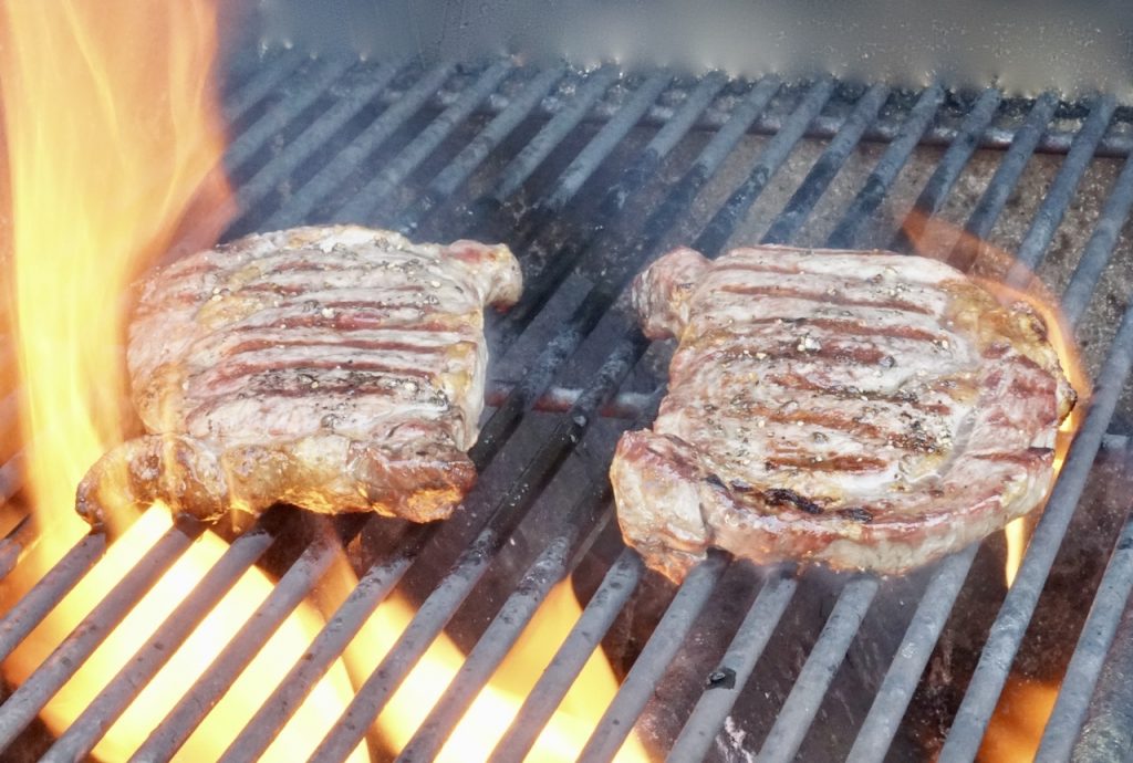 The ribeye steaks on the grill