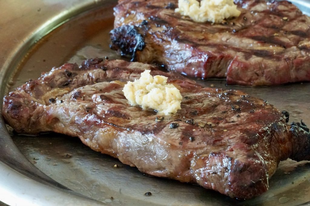 The grilled steaks served with a roasted garlic compound butter
