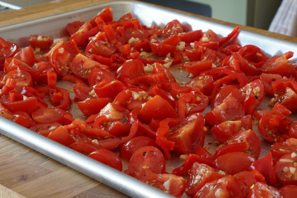 The tomato and pepper mixture sprtead out onto a sheet pan