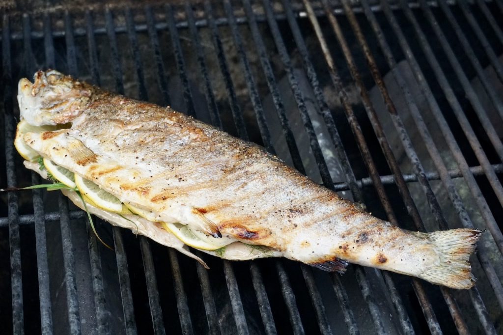 The whole fish flipped and cooking on the grill