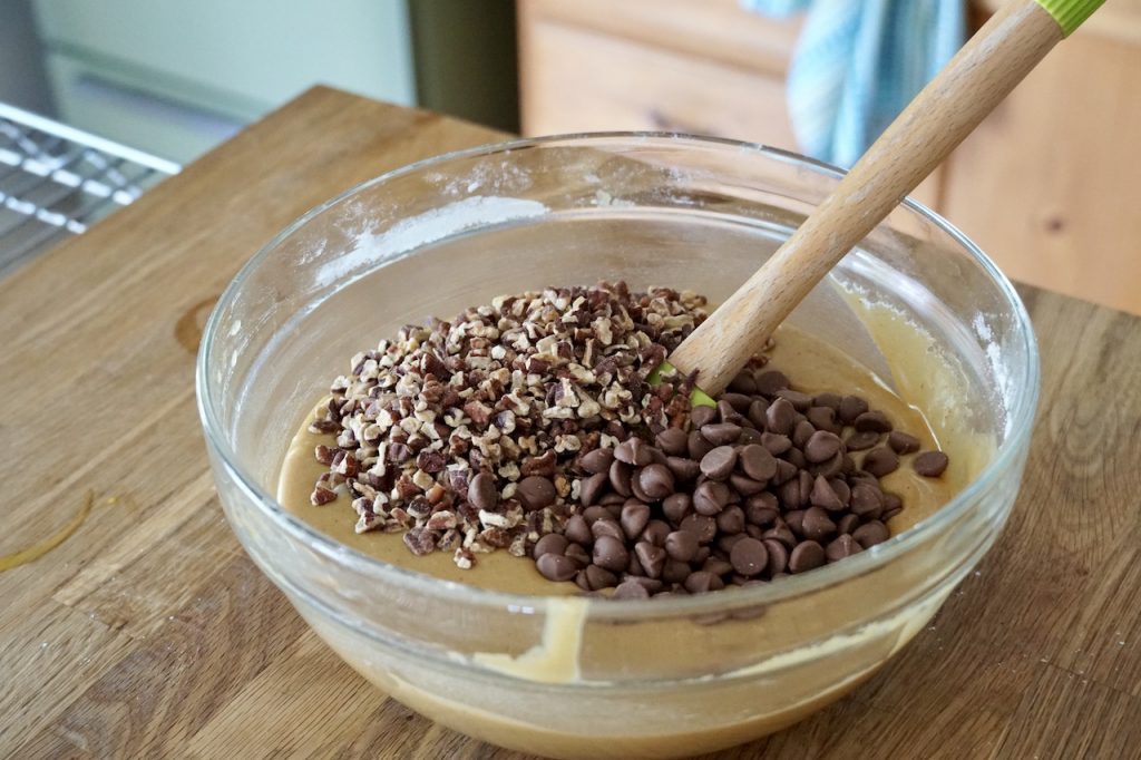 Adding toasted pecan pieces and milk chocolate chips into the batter