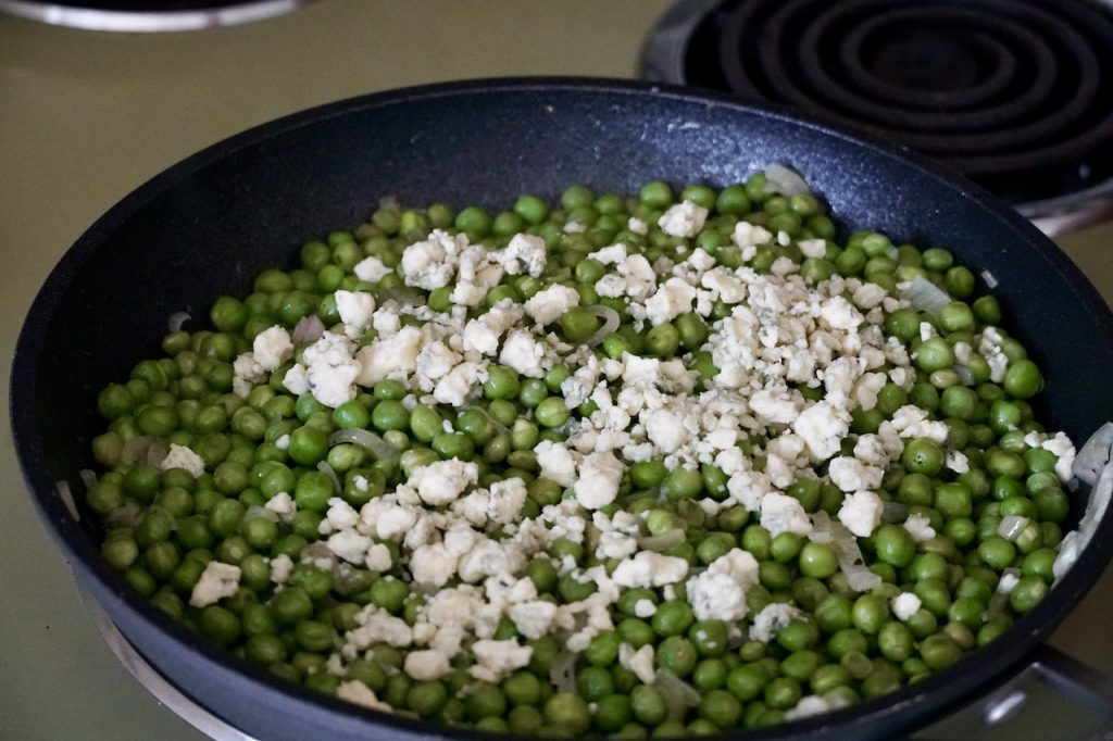The peas sauteed in a large skillet with crumbled blue cheese