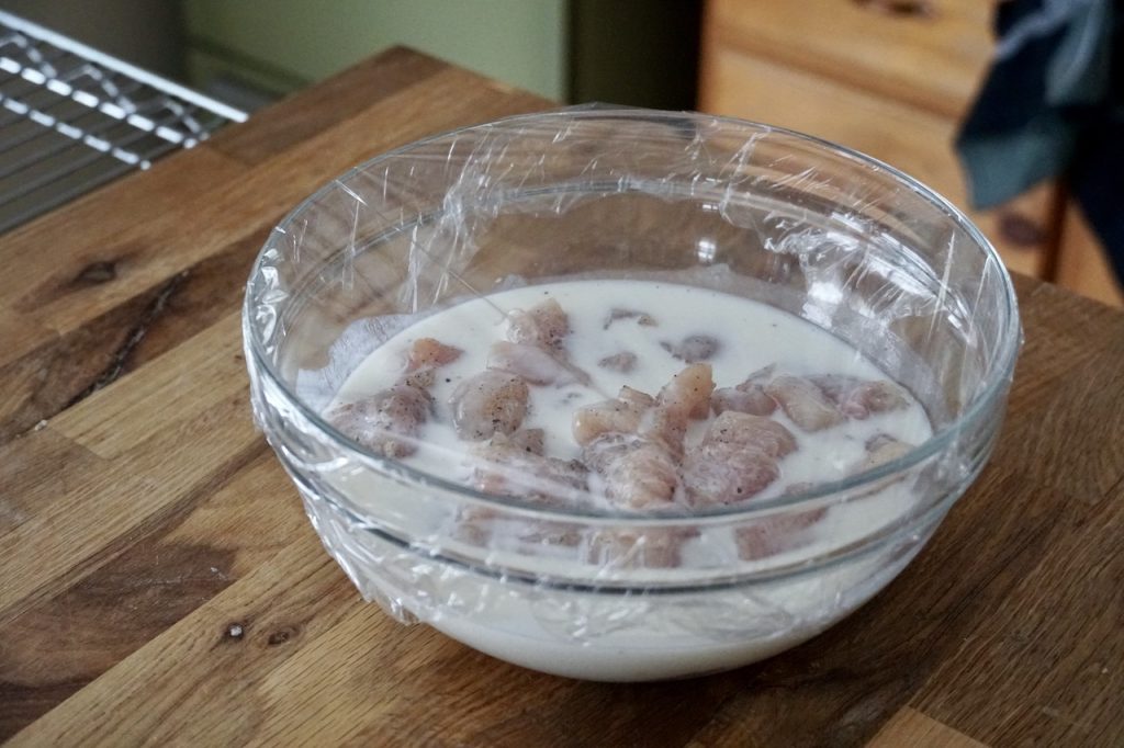 The chicken breasts cut into cubes marinating in buttermilk