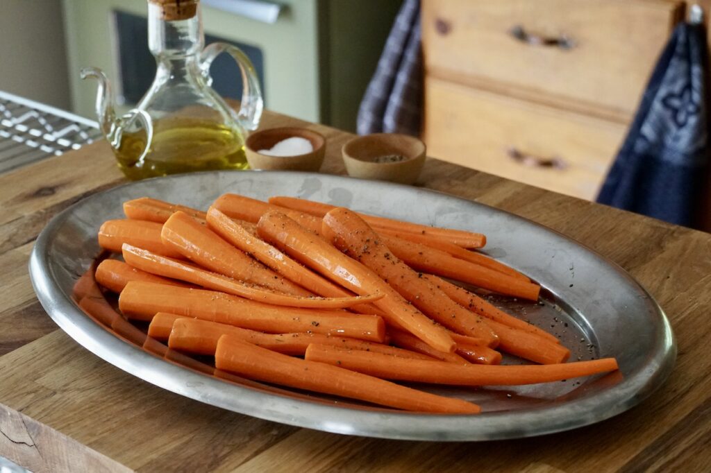 The carrots are tossed in extra virgin olive oil, kosher salt and black pepper.