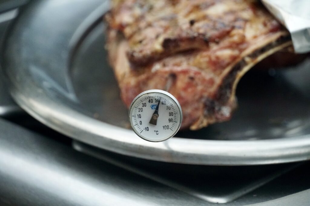 A meat thermometer is inserted in the cooked racks of lamb