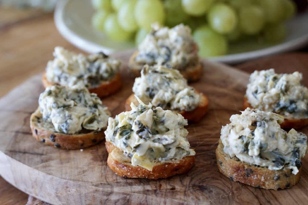 Cheesy spinach artichoke dip served on crispy toasts