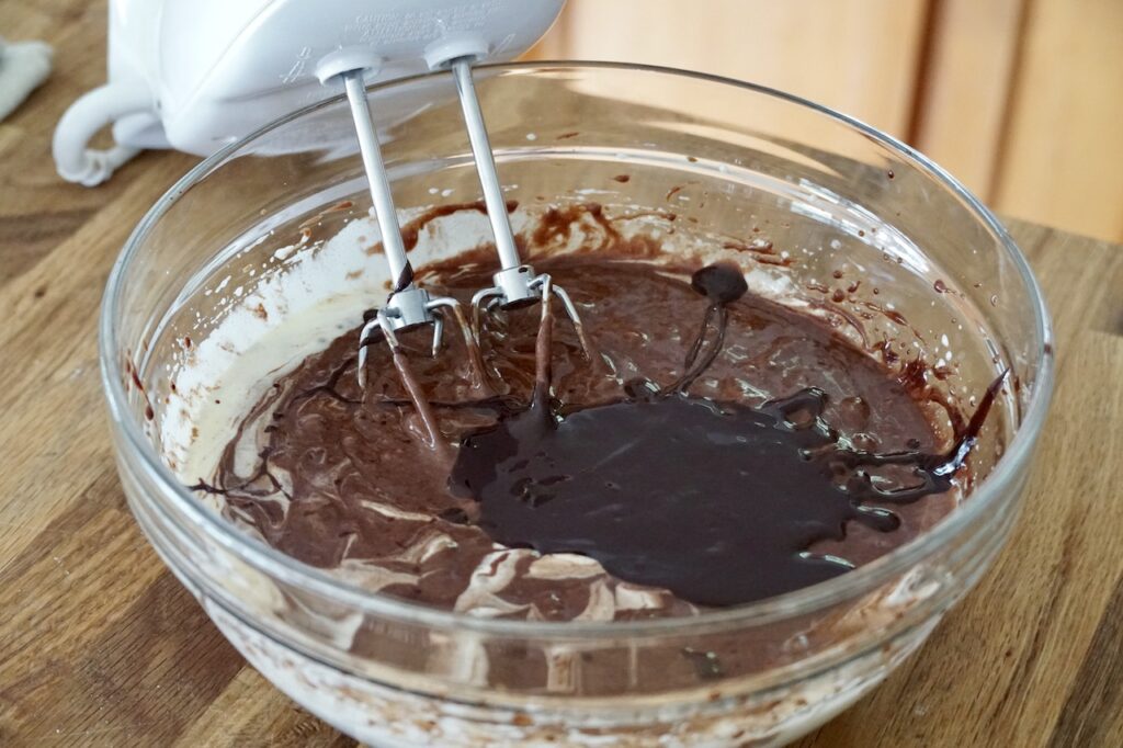 A bowl of the fudgy brownie batter with the chocolate added to the beaten eggs and sugar.