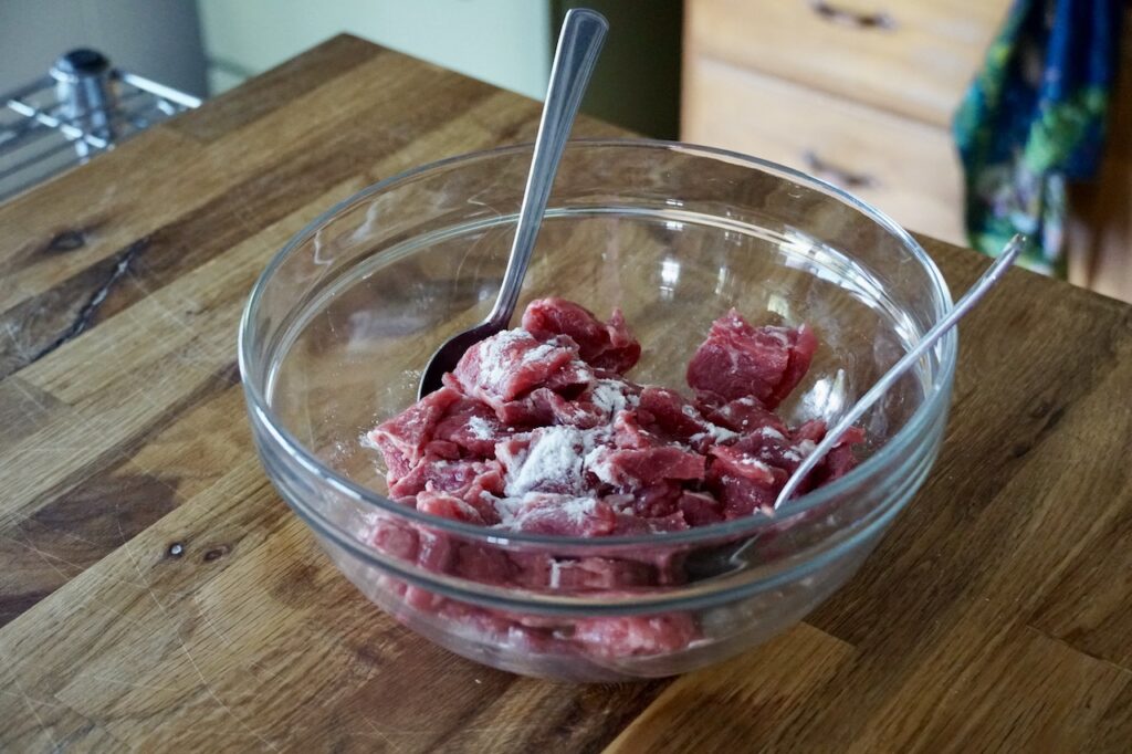 A bowl with the thinly sliced pieces of beef tossed with baking soda.