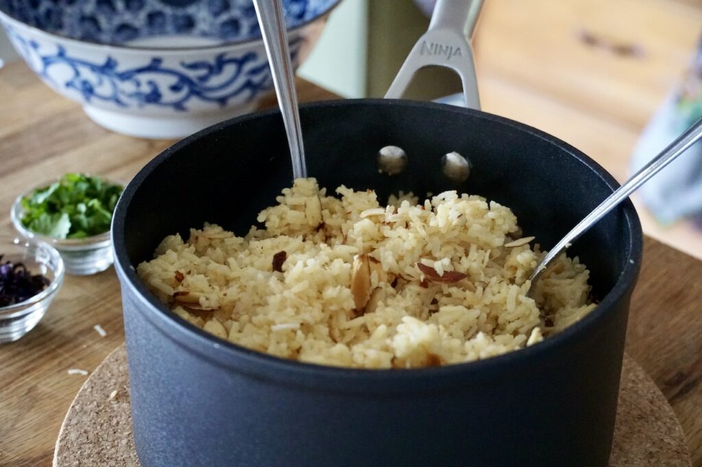 A pot of the finished rice fluffed up with the toasted almonds and coconut.