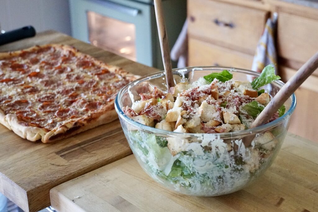 The pizza served with Caesar salad