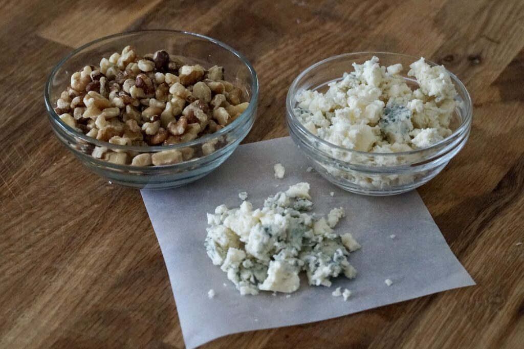 A bowl of toasted walnuts and crumbled blue cheese