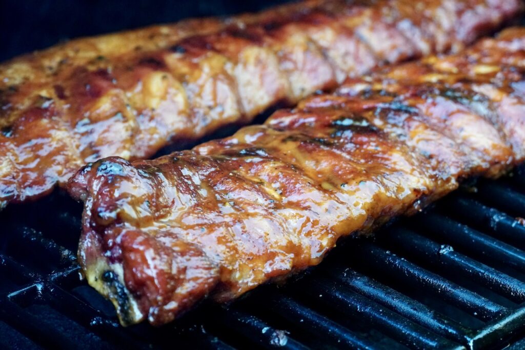 Two racks of ribs on the grill brushed with WATC BBQ Sauce