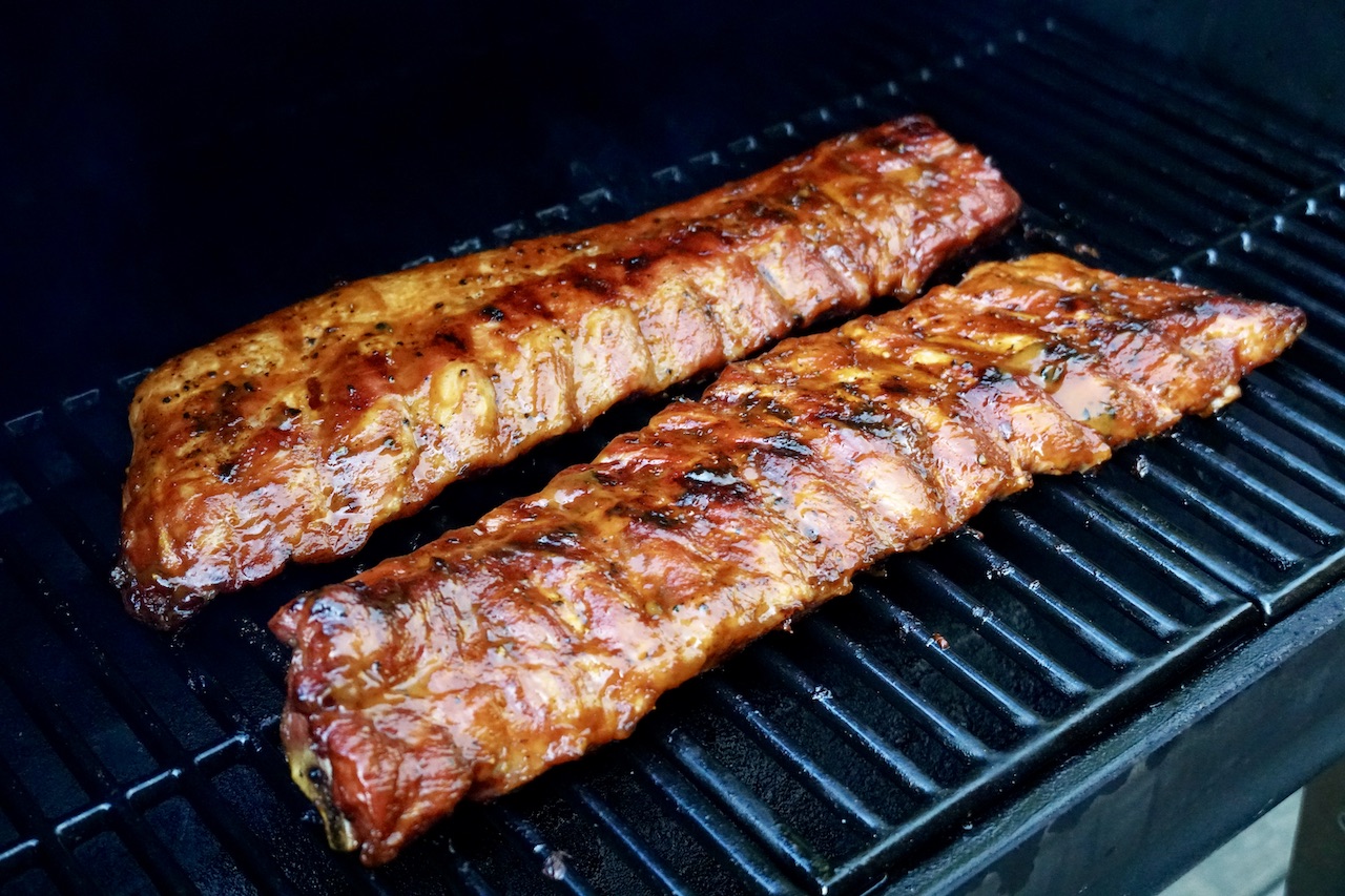 Two rack of tender pork ribs cooking slowly on the smoker