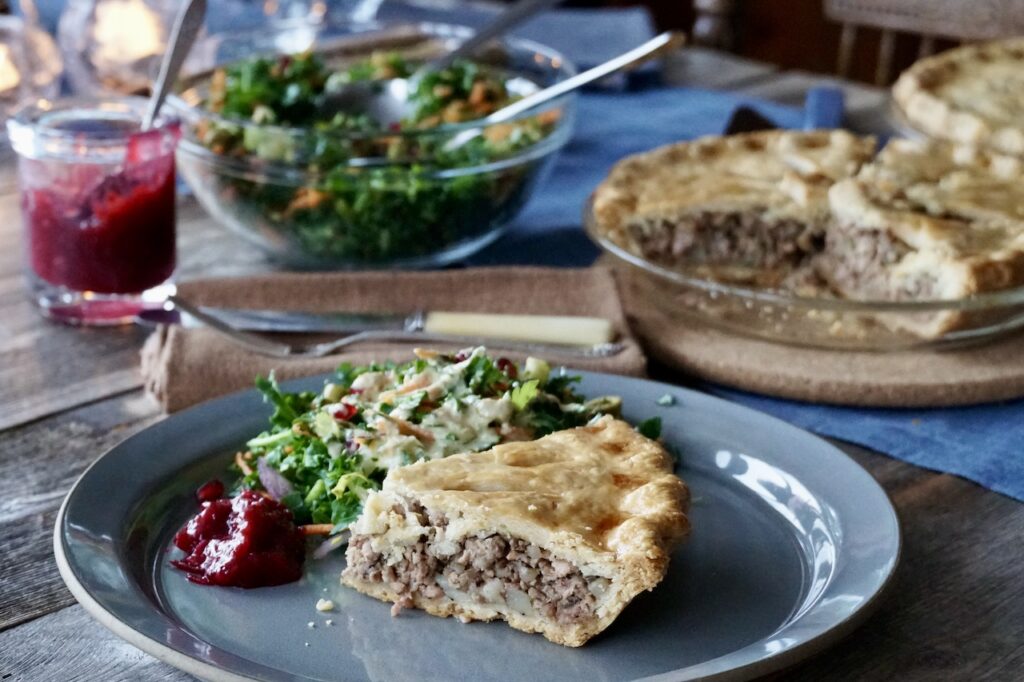 Tourtière served with a fresh salad and a dollop of tangy cranberry sauce.