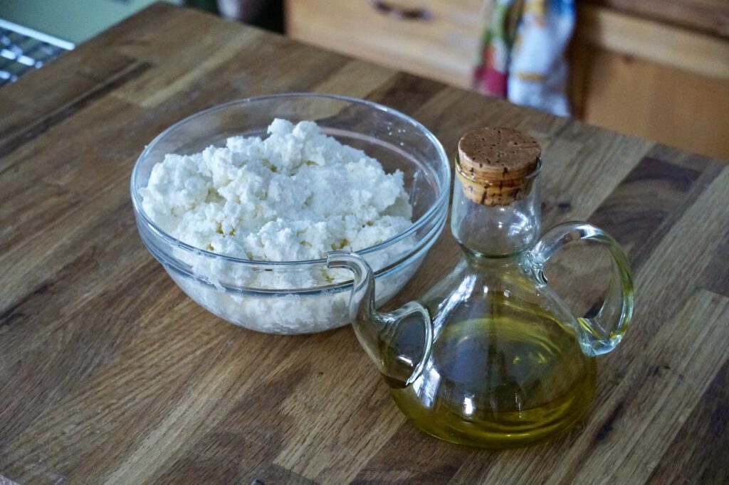 A bowl of ricotta cheese and a carafe of extra virgin olive oil.