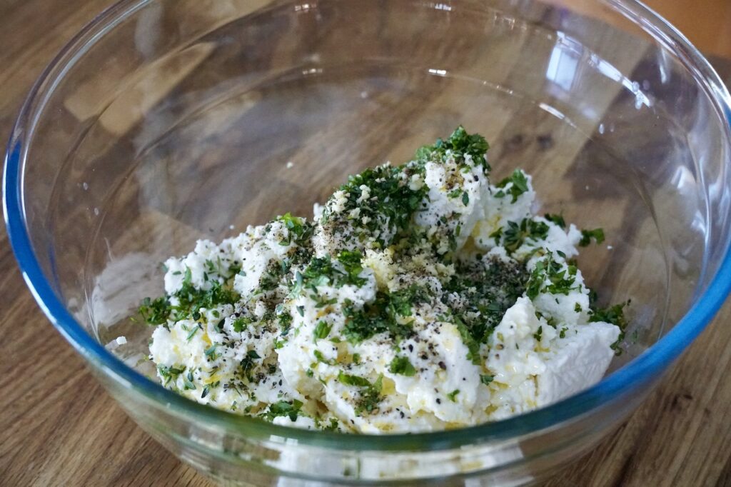 The ricotta, fresh herbs, garlic and pepper in a bowl, ready to be whipped.