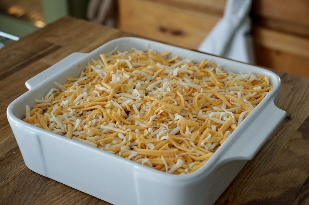The beef taco dip covered with grated cheese, ready for the oven.