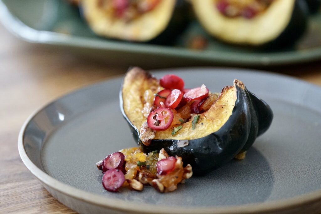 A portion of the oven-baked acorn squash presented with the flavourful topping cascading down onto a side plate.