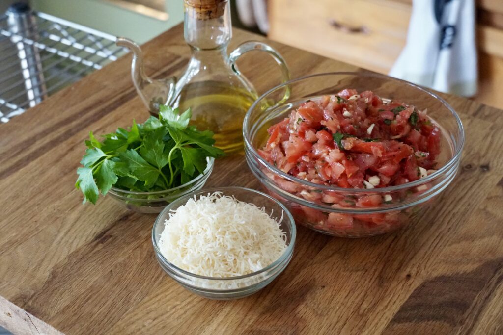 A bowl of the chopped tomato mixture, Parmesan cheese, chopped parsley and extra virgin olive oil.