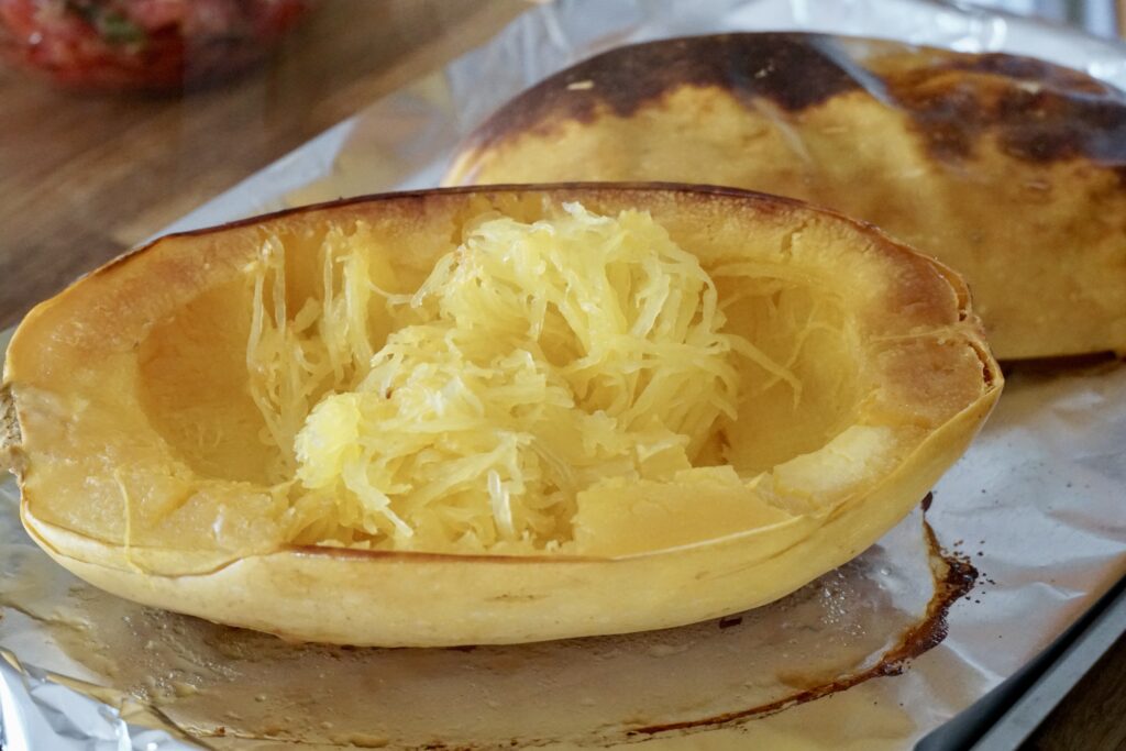 The cooked spaghetti squash scooped up to reveal the spaghetti texture.