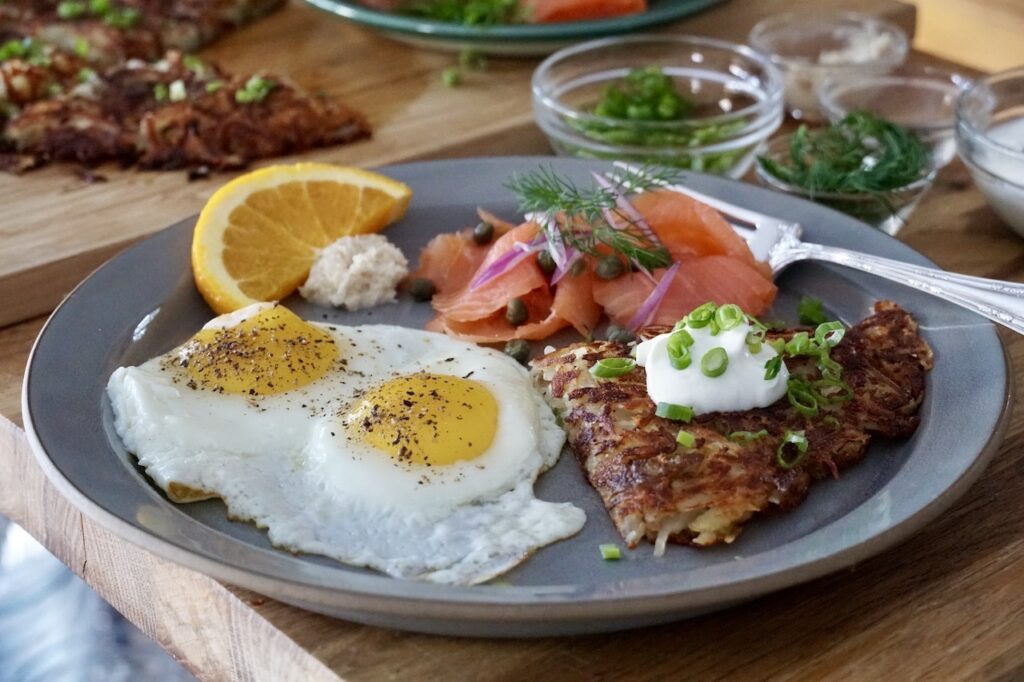 Rösti potatoes served on a plate with smoked salmon and fried eggs.