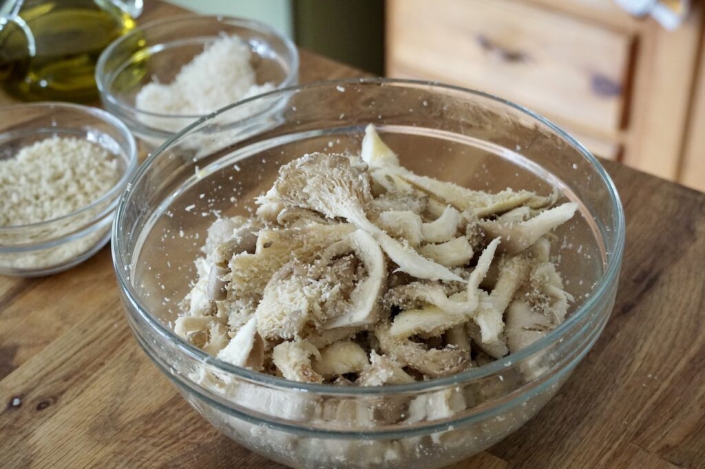 A large bowl filled with the mushrooms coated with Parmesan and panko crumbs.