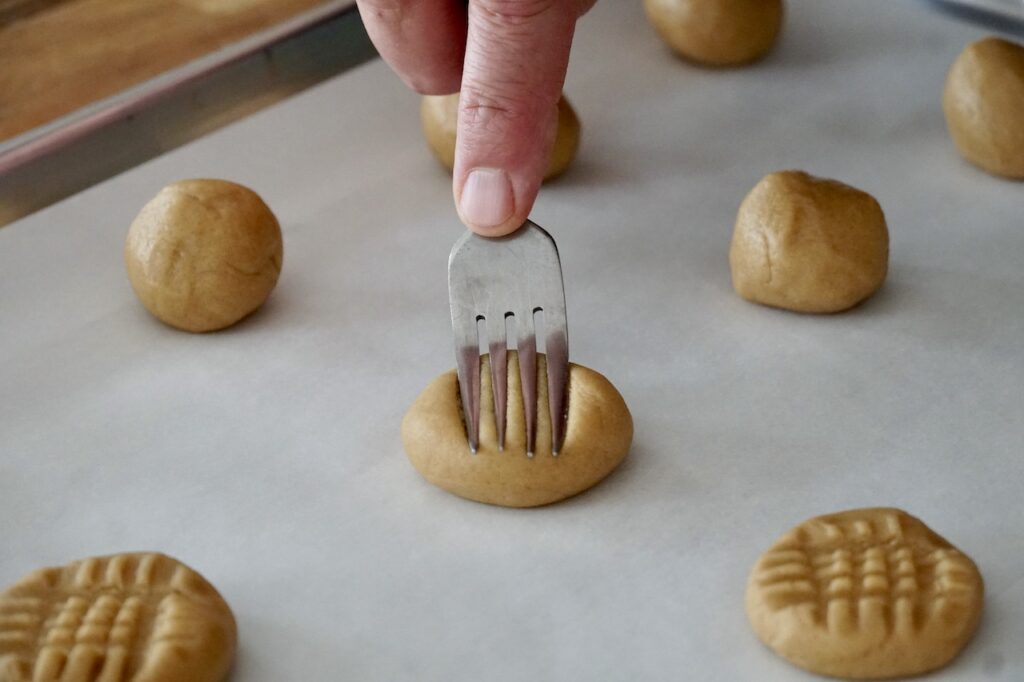 A fork pressing down into the dough to create the classic crisscross detail.