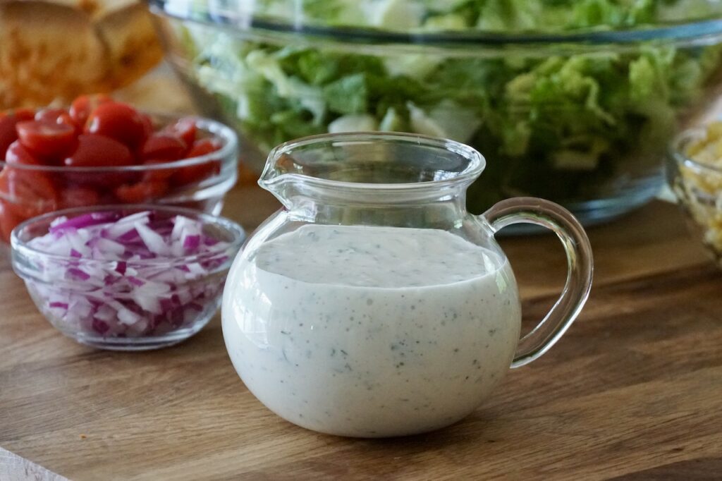 A small pitcher filled with creamy buttermilk ranch dressing.