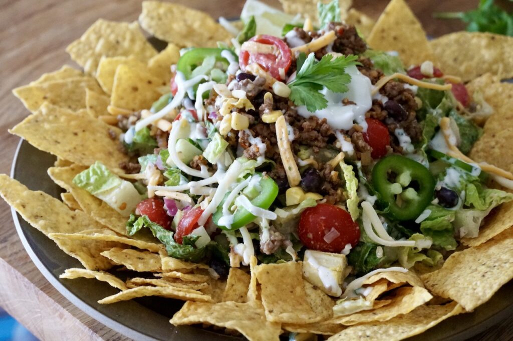 Tex-Mex Taco Salad served on a large plate surrounded by crispy corn tortilla chips.