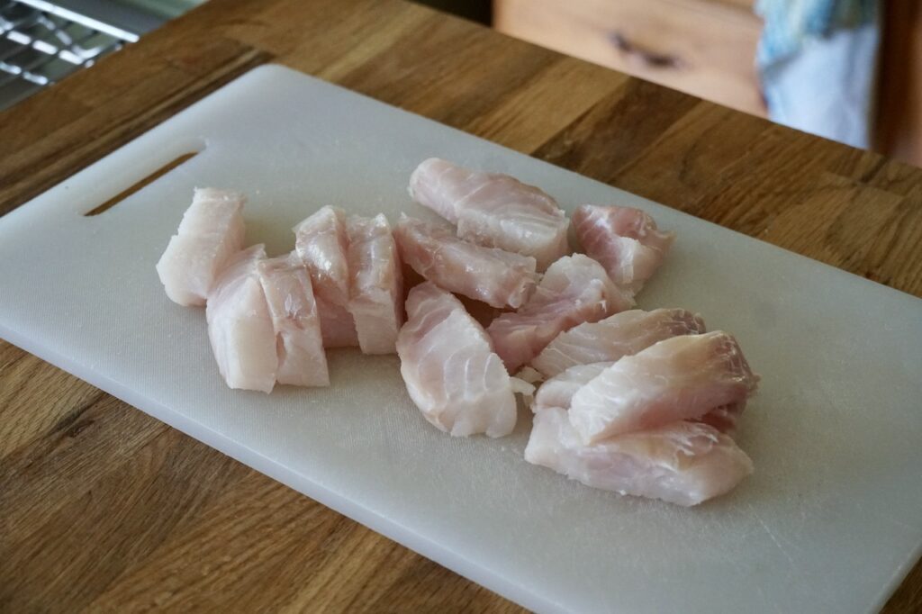 Strips of fresh cod on a cutting board.