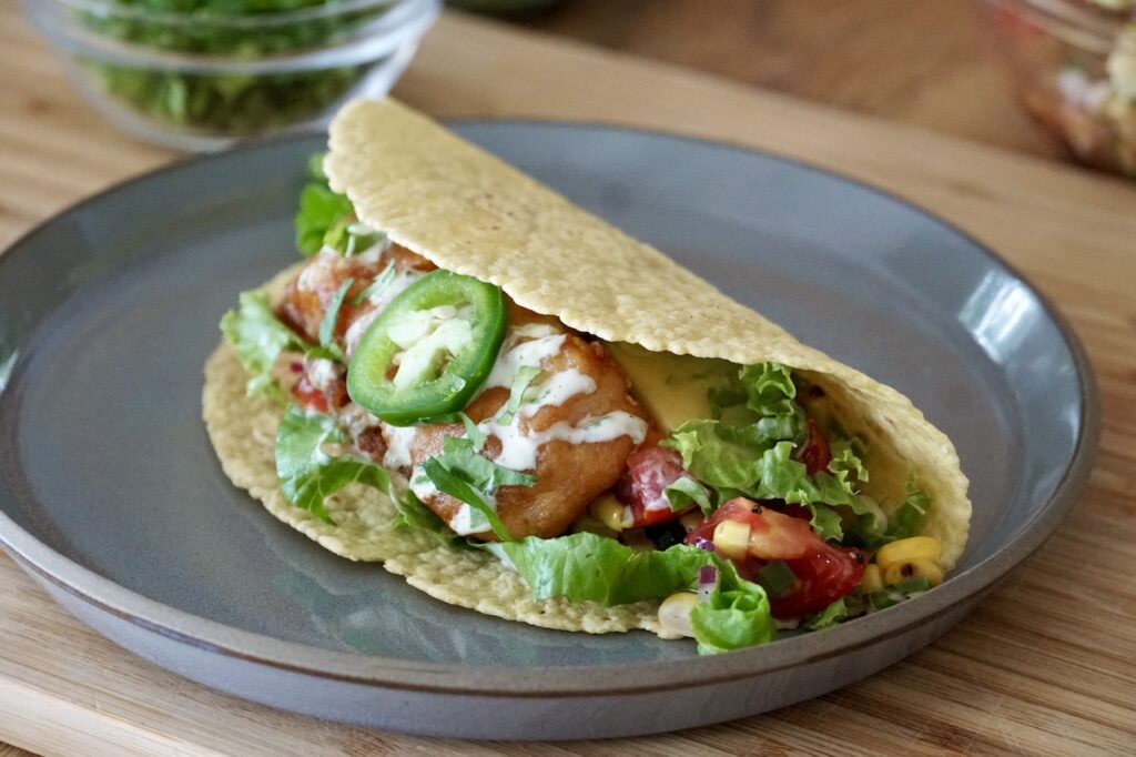 A fish taco sitting on a luncheon plate.