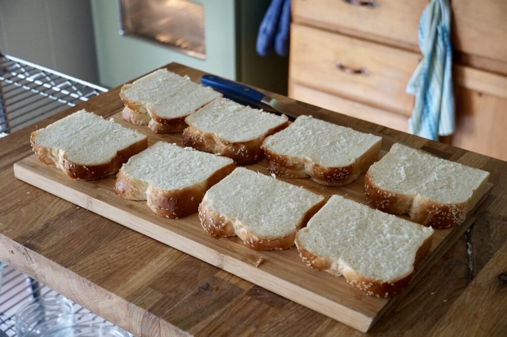 The slices of bread spread out on a cutting board to dry our a bit.